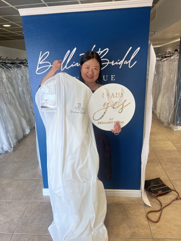 Ying said yes to the dress at Brilliant Bridal Las Vegas. Ying his holding a sign saying "I said yes to the dress" while holding her gown up in a garment bag.