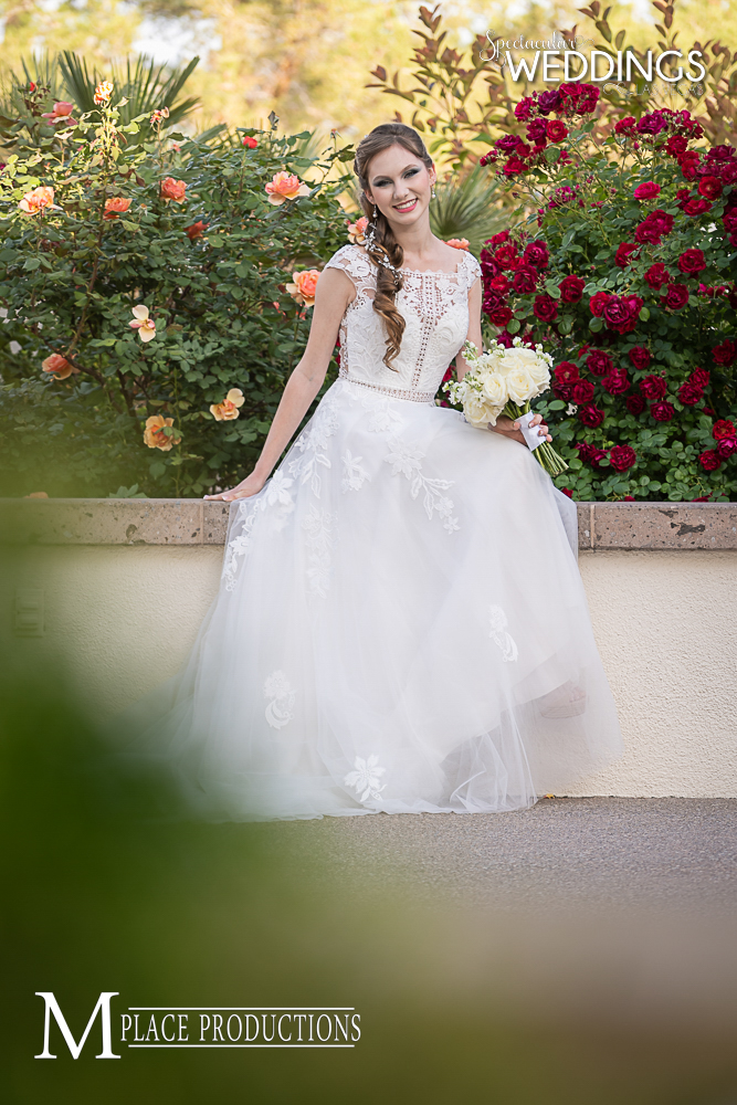 Bride wears trending wedding gown while poses in front of blooming rose bushes at Emerald at Queensridge